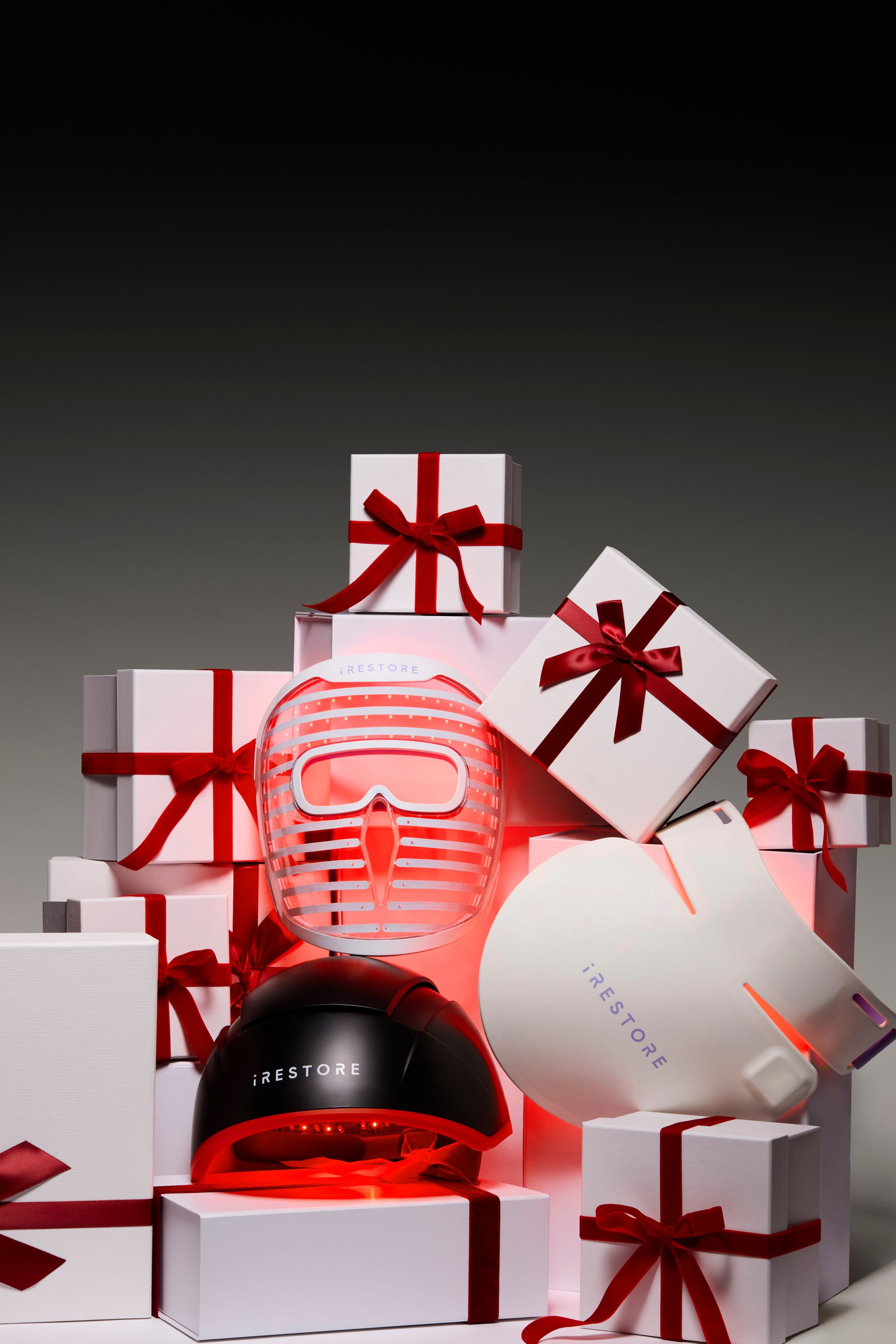 iRESTORE light therapy devices surrounded by holiday gifts tied with red ribbons