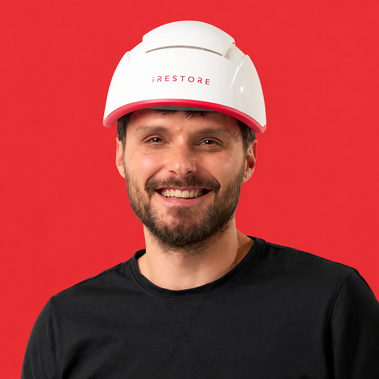 Smiling man wearing an iRESTORE red light therapy device