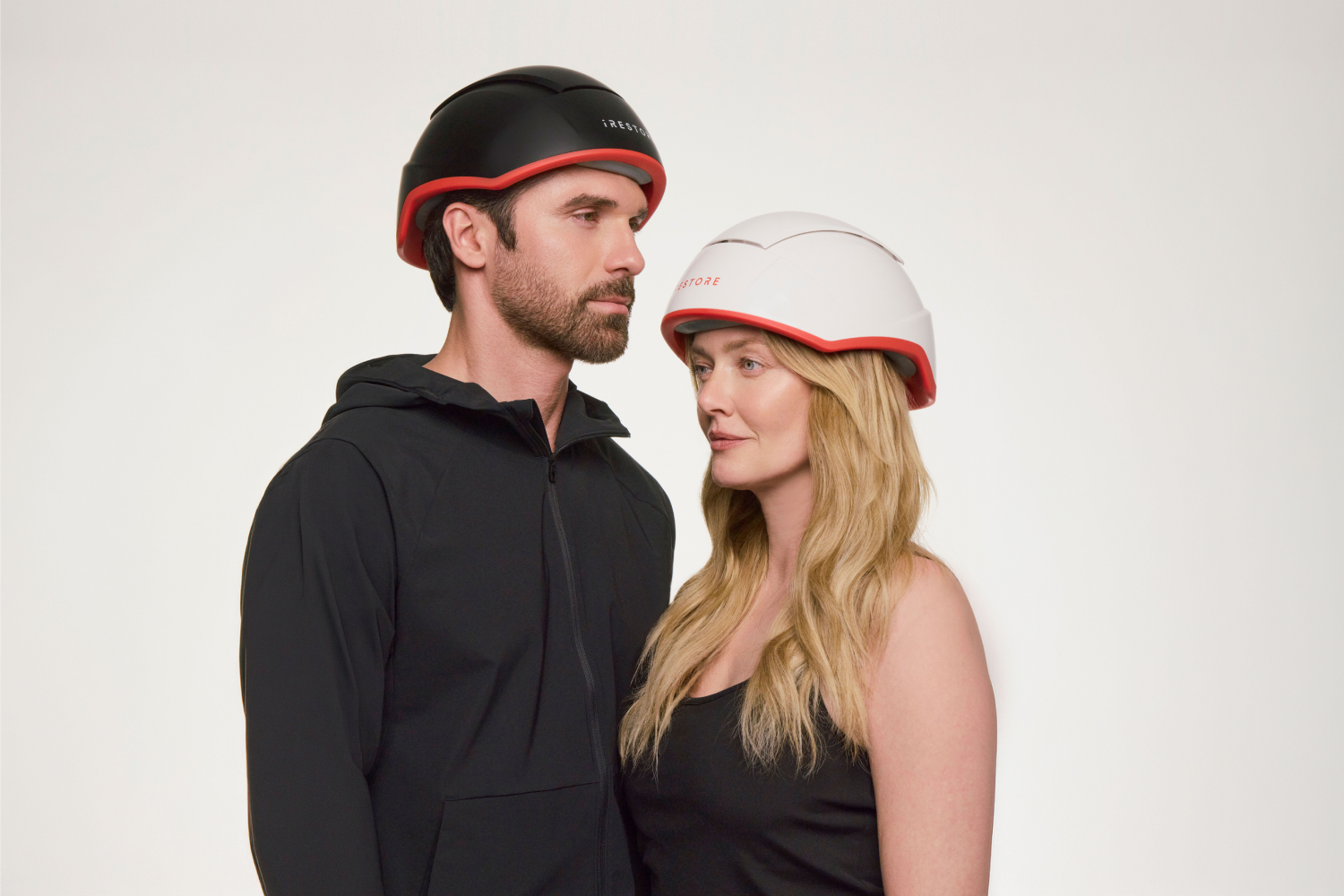 A man and woman wearing iRESTORE hair growth devices