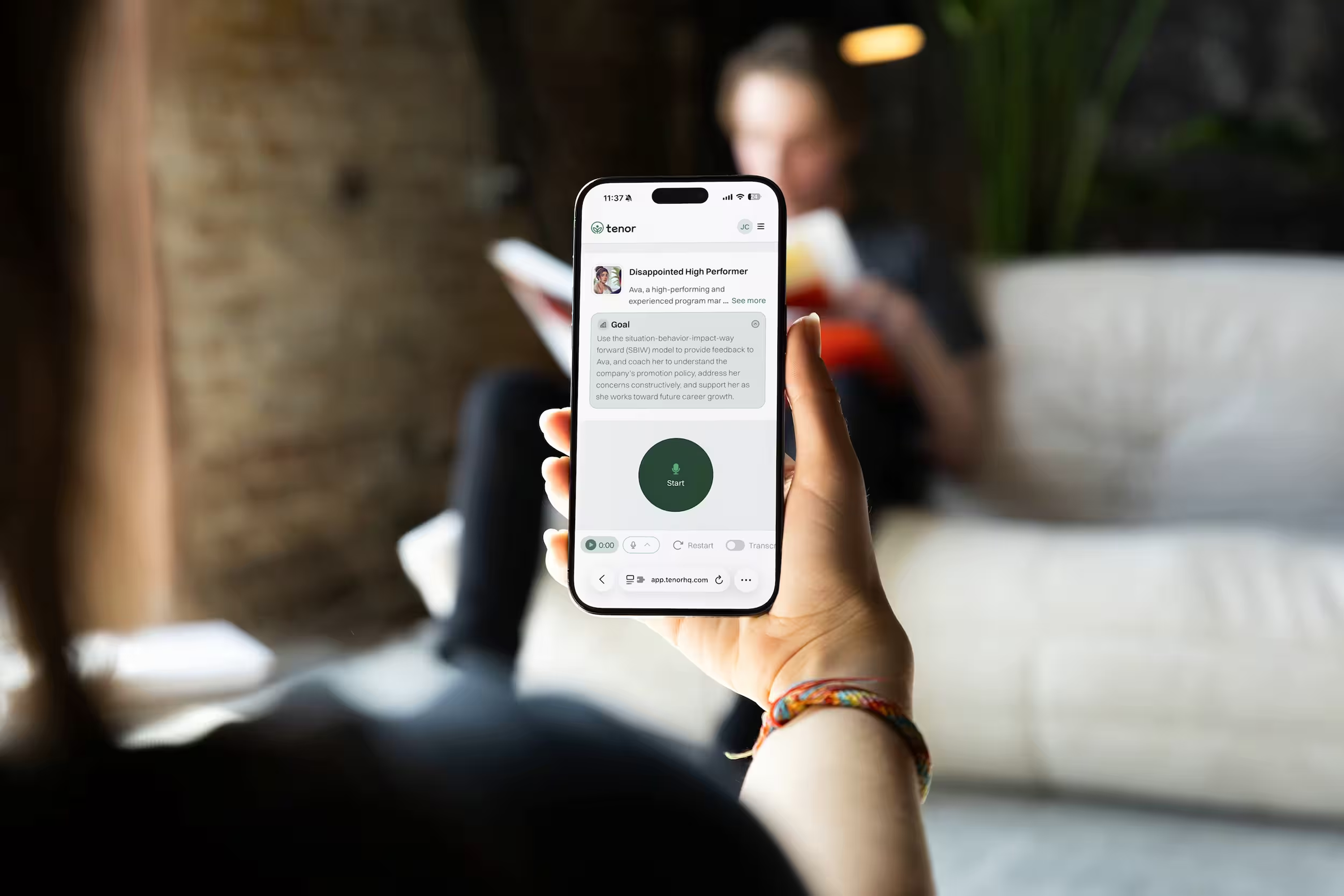 A person holds up a smartphone displaying a messaging or audio screen