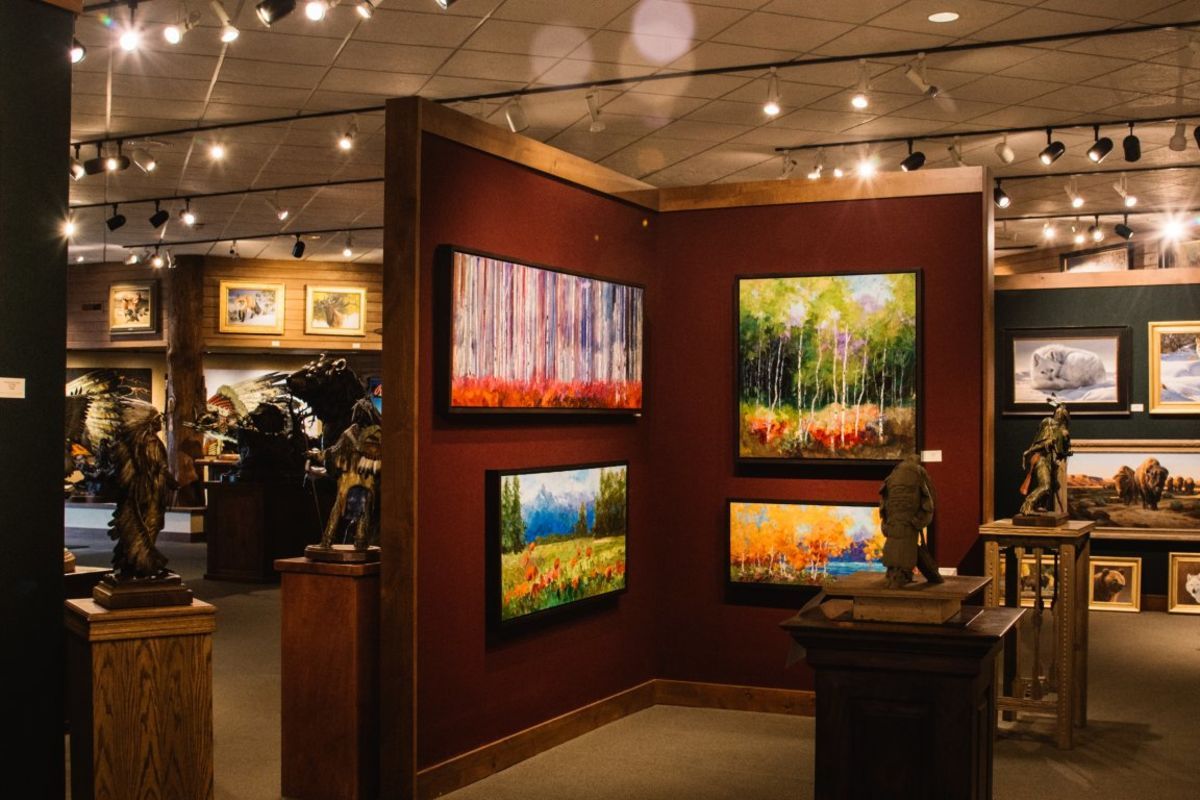 Art gallery in Jackson Hole with vibrant western landscape paintings on burgundy walls