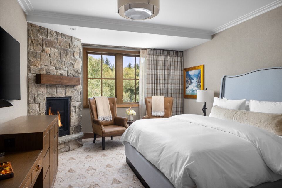 Rusty Parrot Lodge king room with stone fireplace, plush bedding and mountain lodge decor
