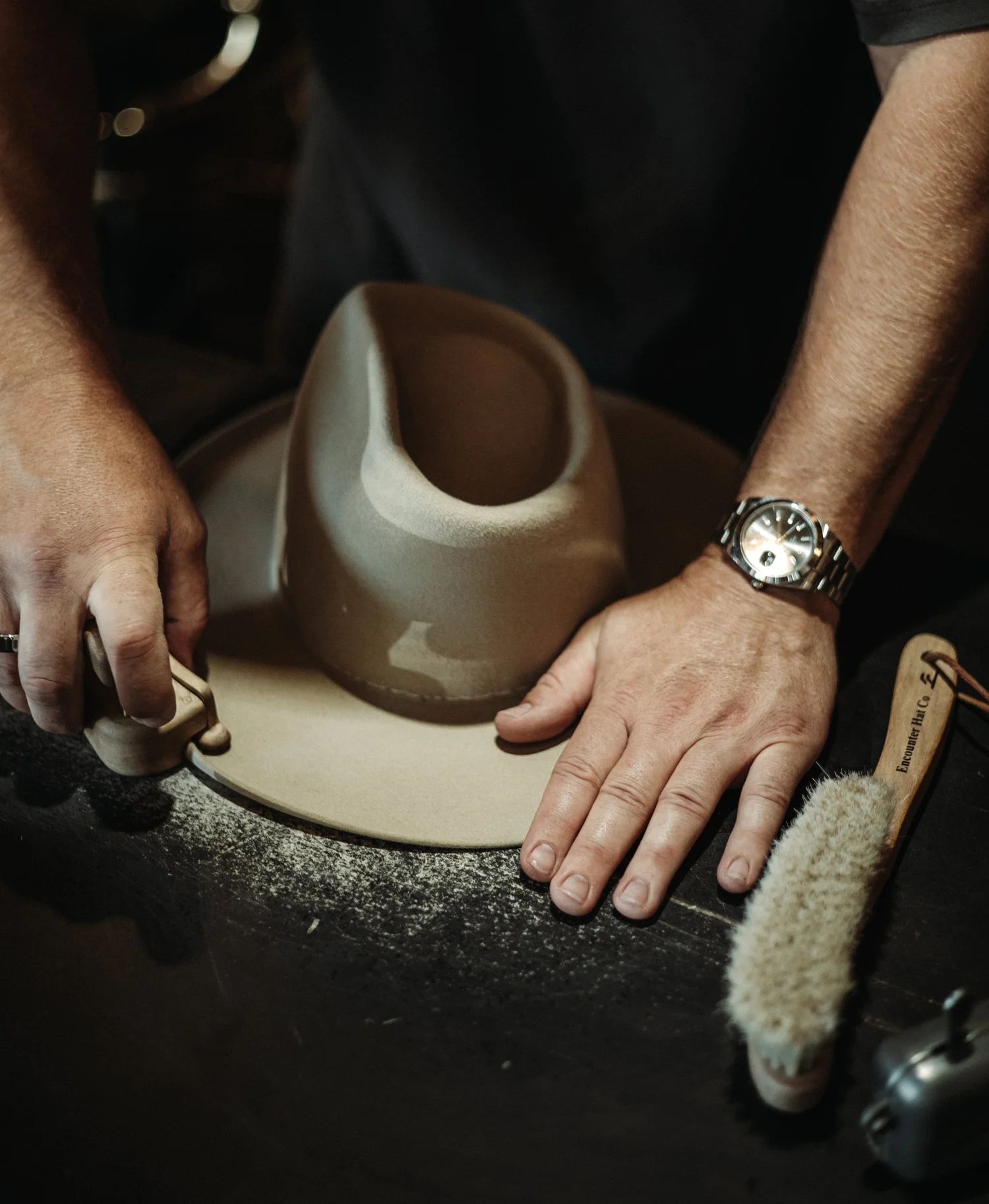 Craftsman's hands shaping a custom western hat on a blocking form at Encounter Hat Co in Jackson Hole