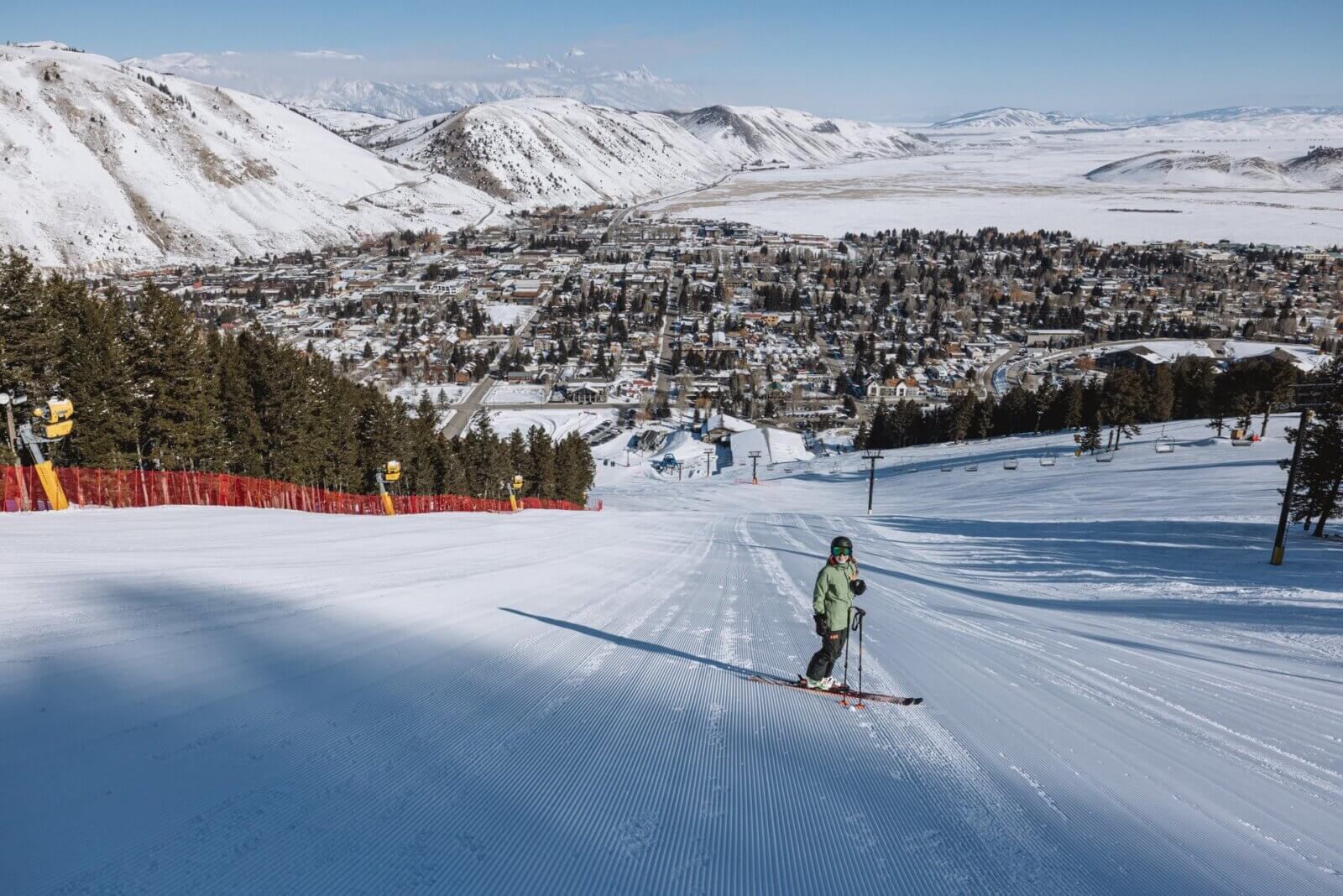 Skier descending groomed slope at Snow King with Jackson town valley below