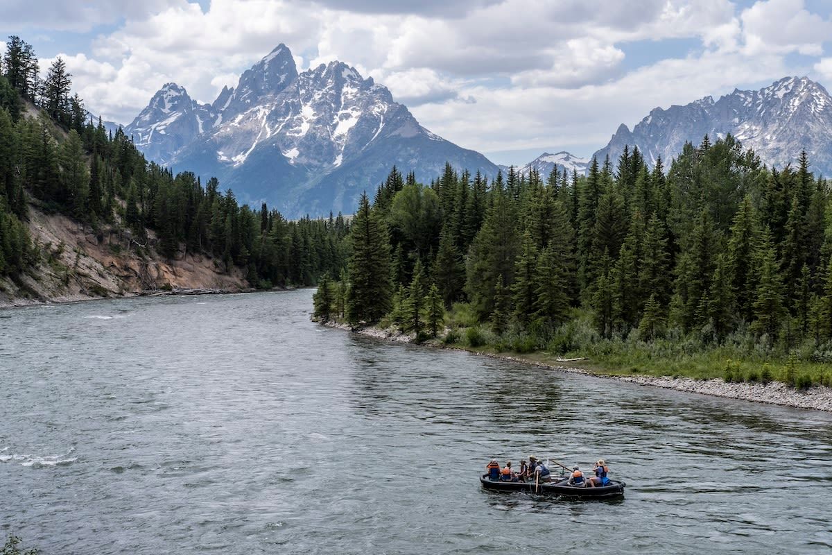 Raft floating the Snake River with Grand Teton peaks rising in the background