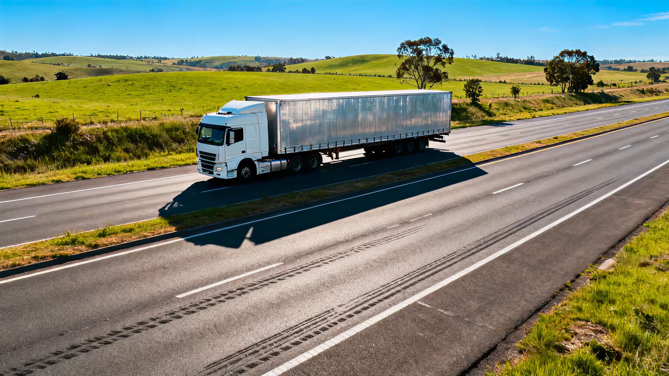 A semi-truck traveling through green farmland