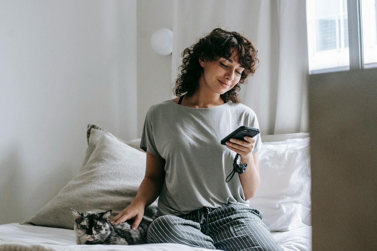 Woman relaxing comfortably at home, reviewing her care plan on her phone