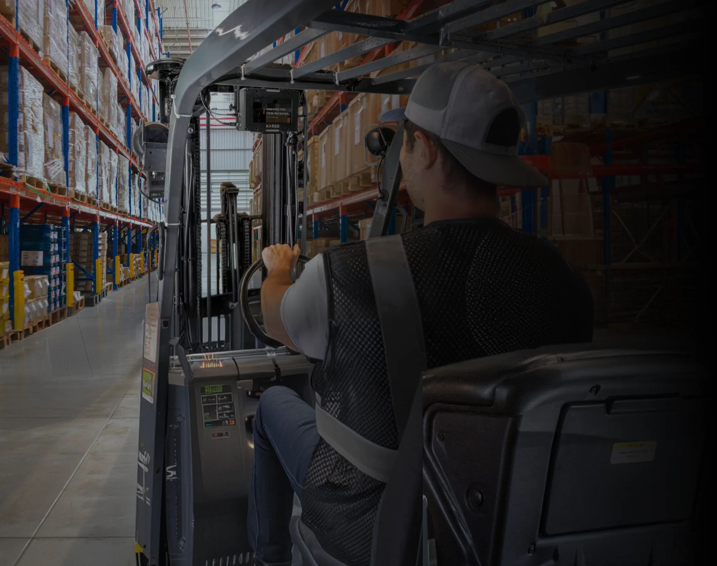 Forklift operator driving down a tall, organized warehouse aisle