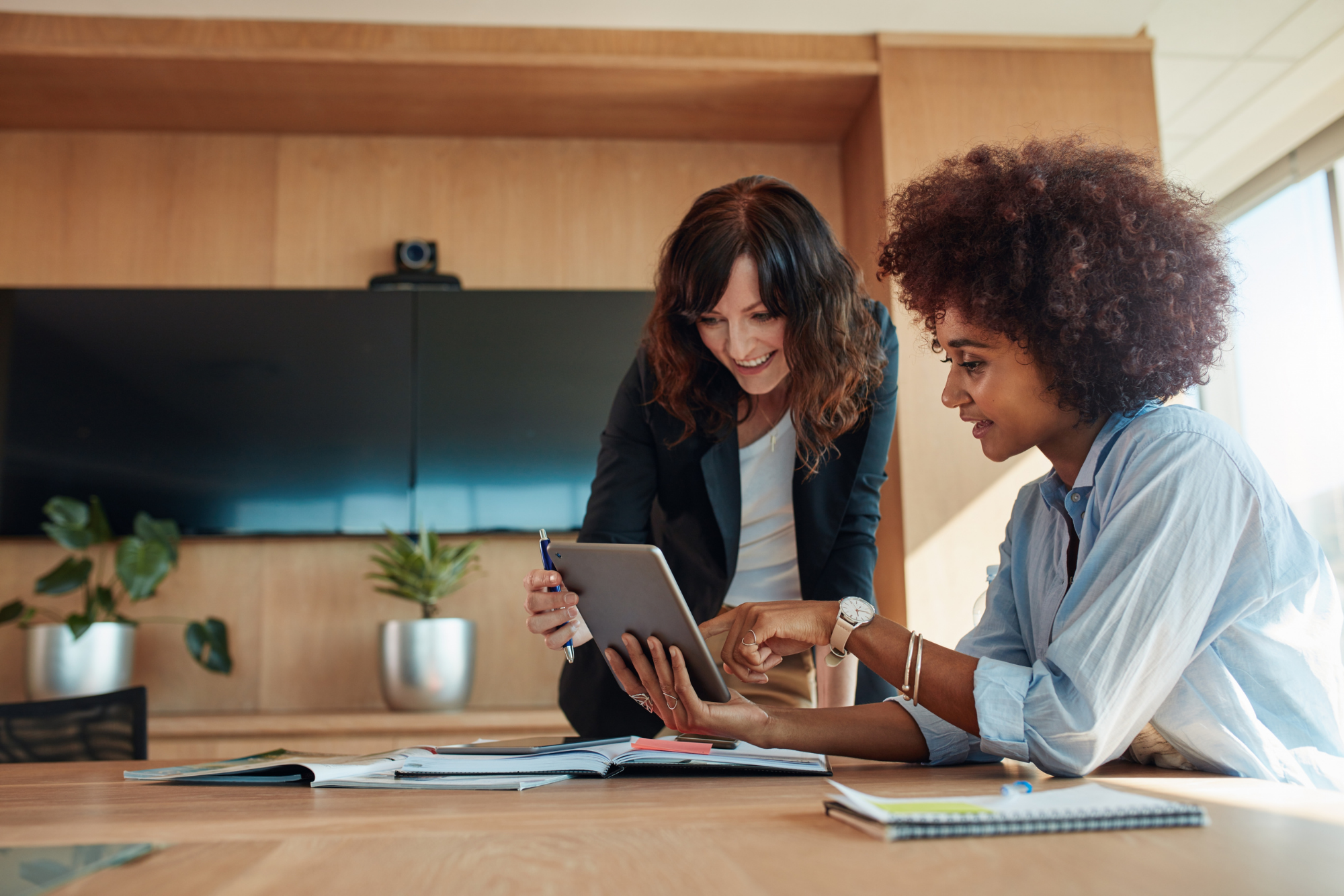 Two colleagues collaborating over a tablet at an office desk