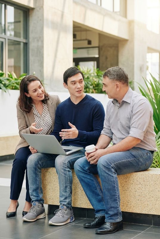 Three professionals in business casual clothing having a collaborative conversation in a modern office