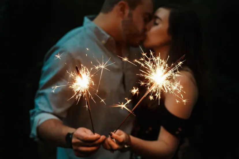 A couple kissing while holding sparklers in the dark