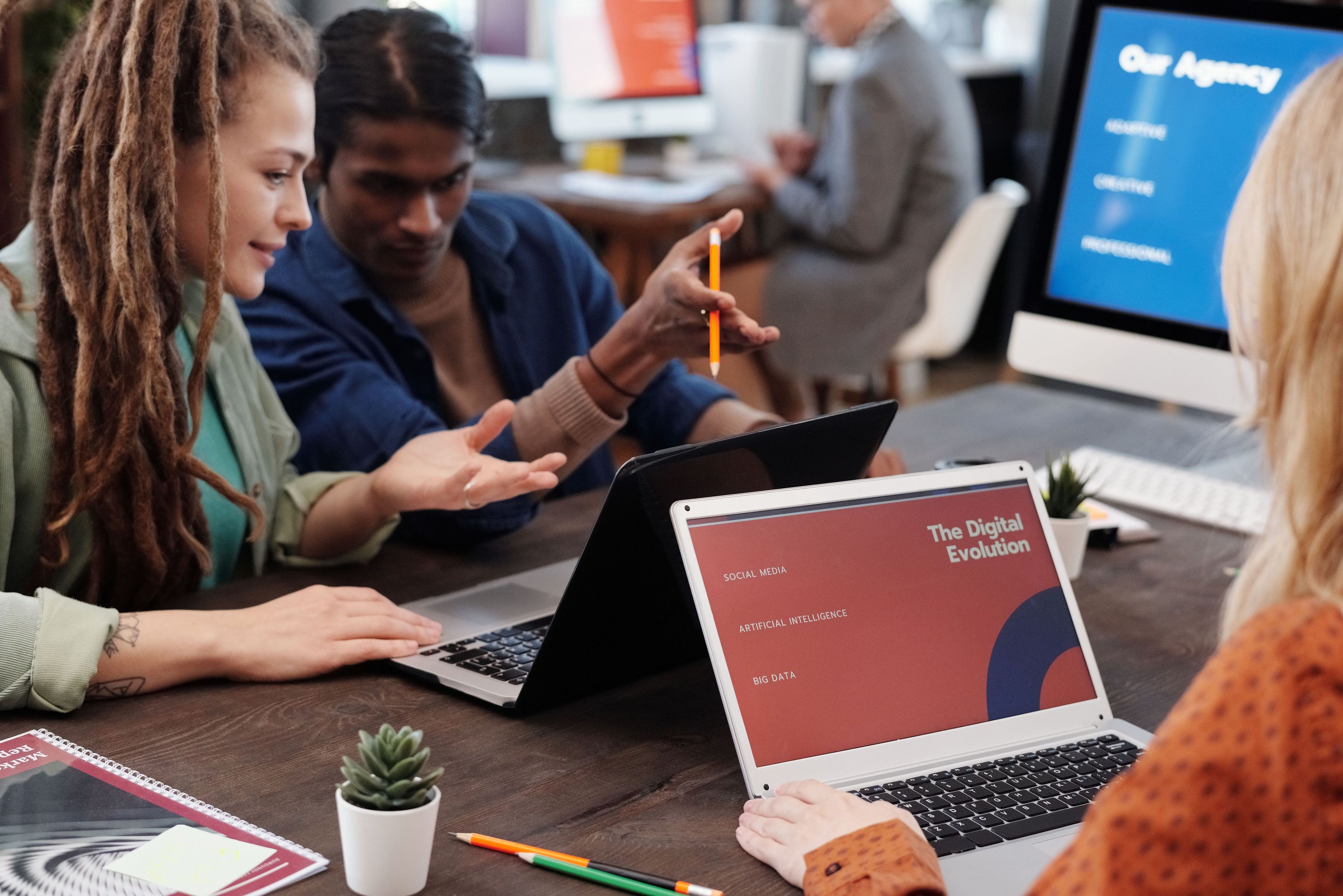Coworkers collaborating around laptops displaying digital marketing presentations