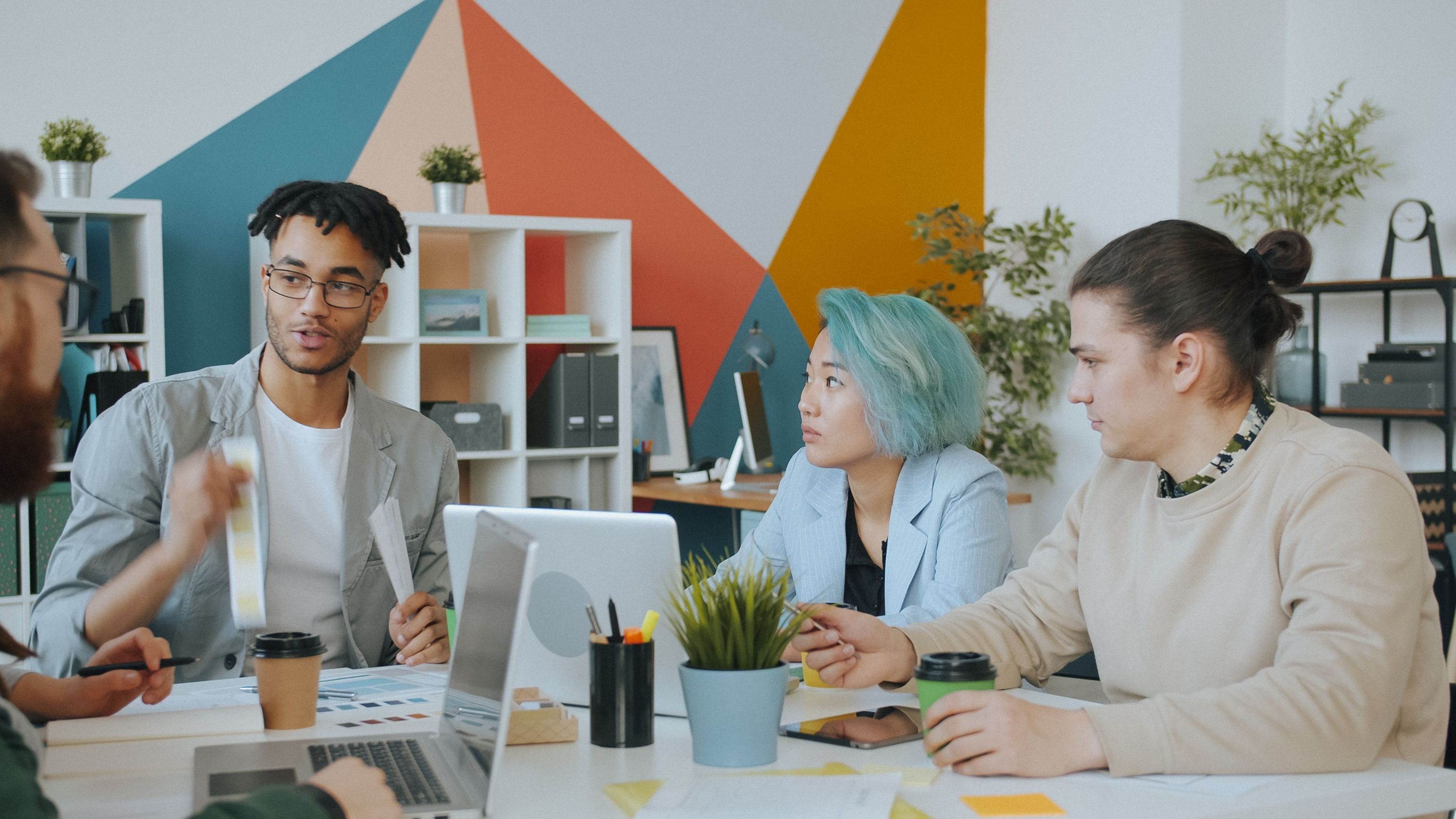 Coworkers collaborating around a laptop in a colorful office