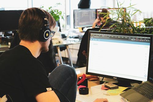 Developer wearing headphones working at a computer in a bright office