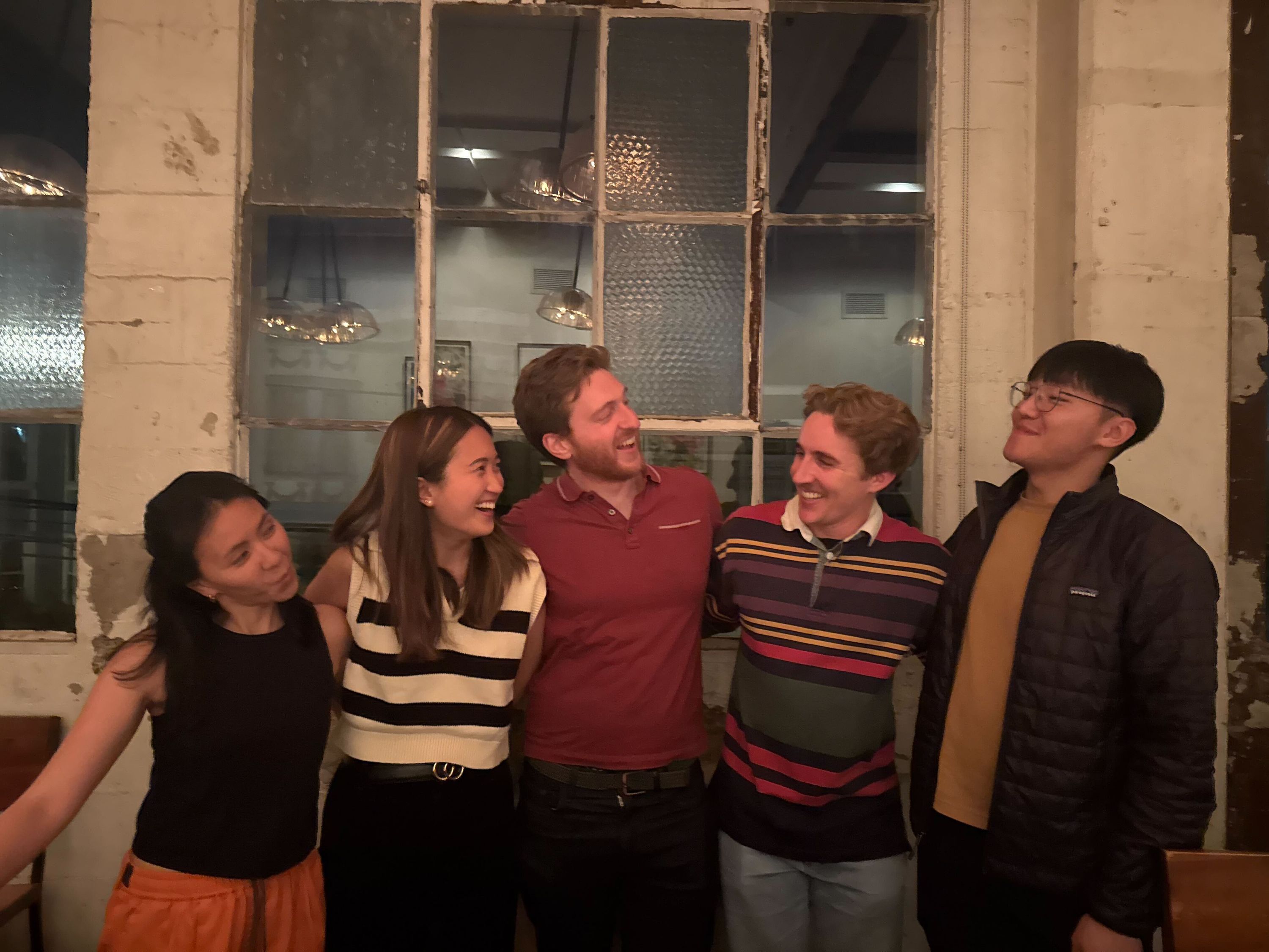 Team members in a casual group pose by grid windows in a rustic-industrial space
