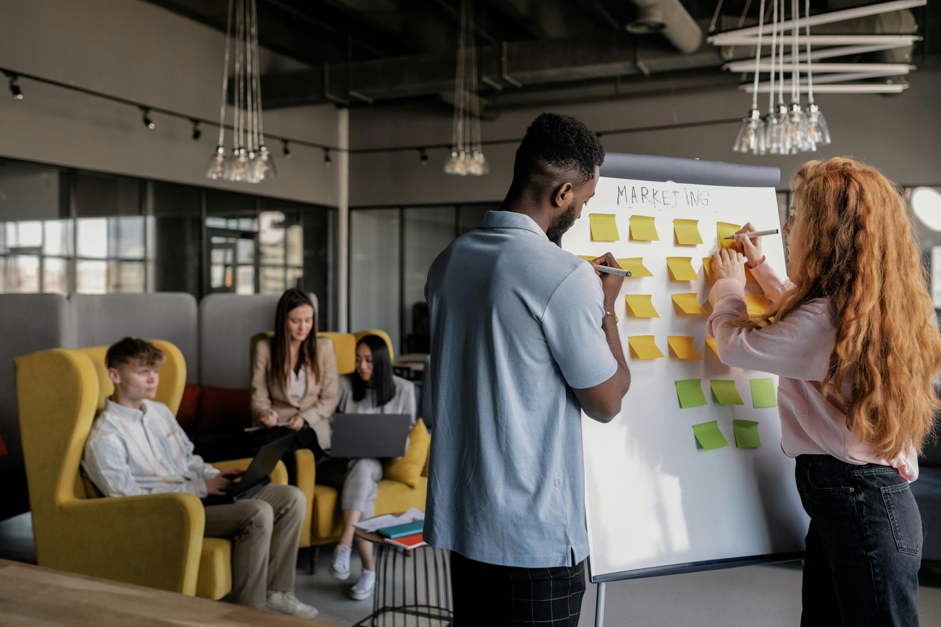 Team collaborating around a whiteboard with sticky notes planning a marketing strategy