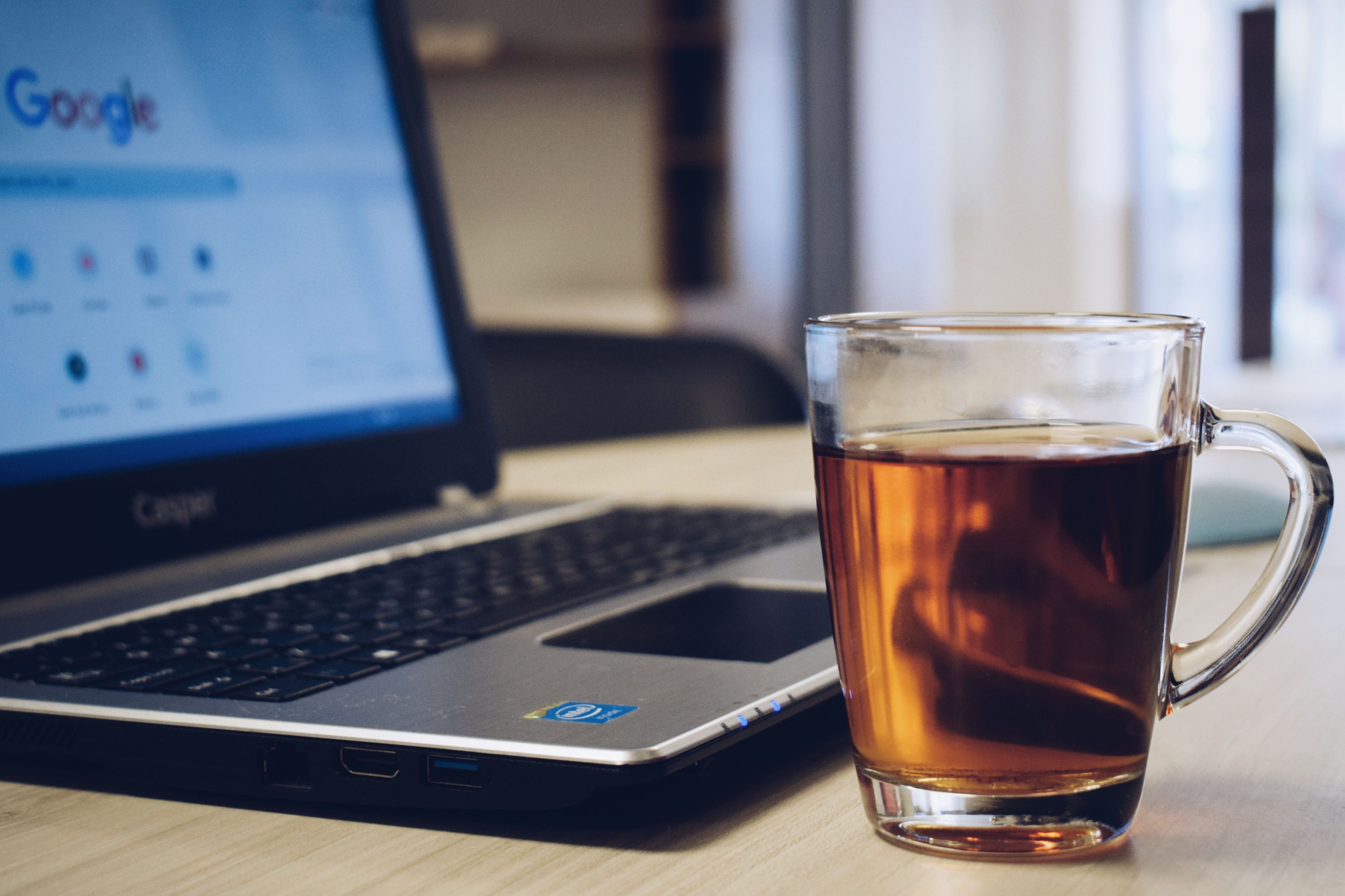 A glass of tea beside a laptop displaying Google search