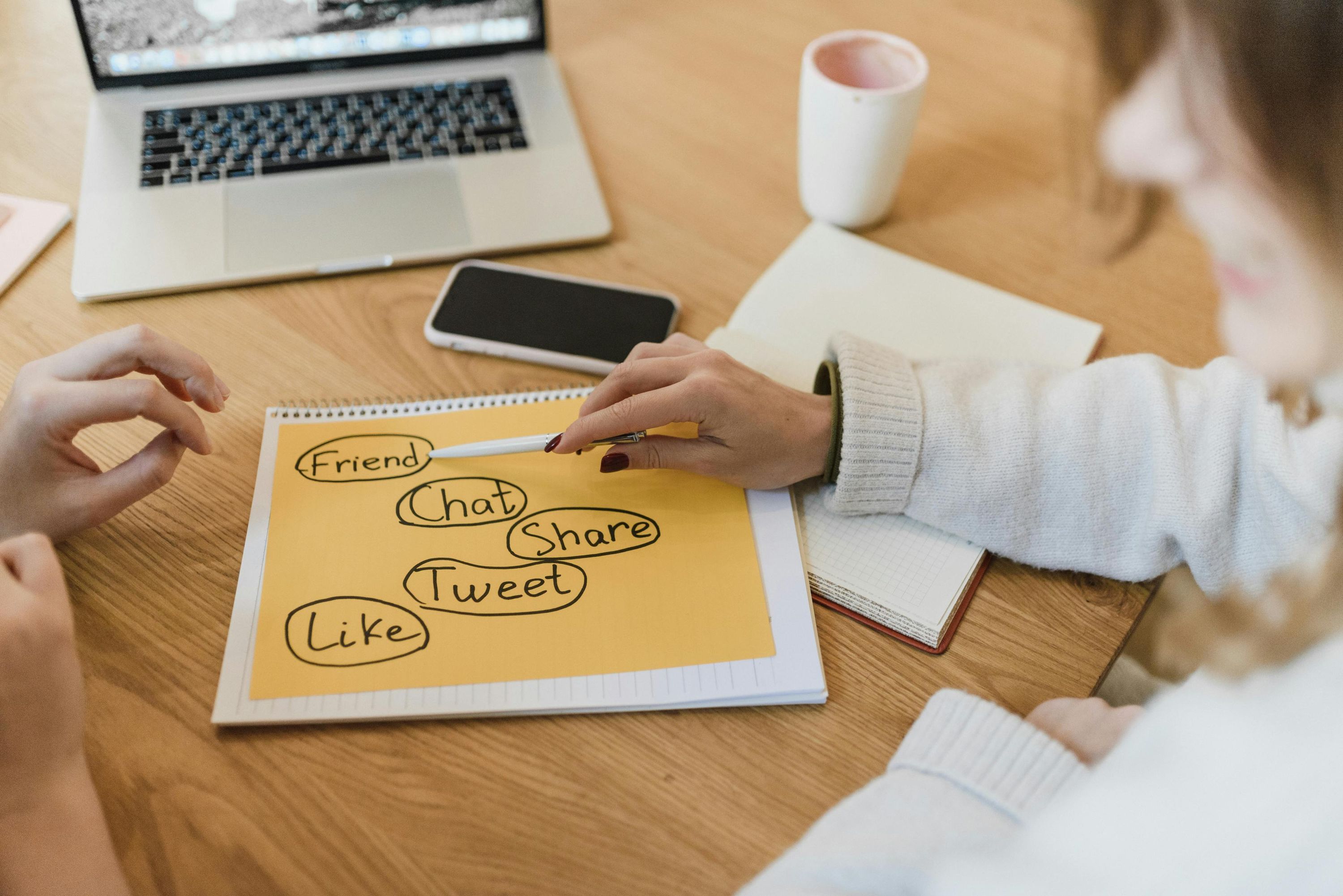 Two women planning a marketing campaign on a notebook at a desk