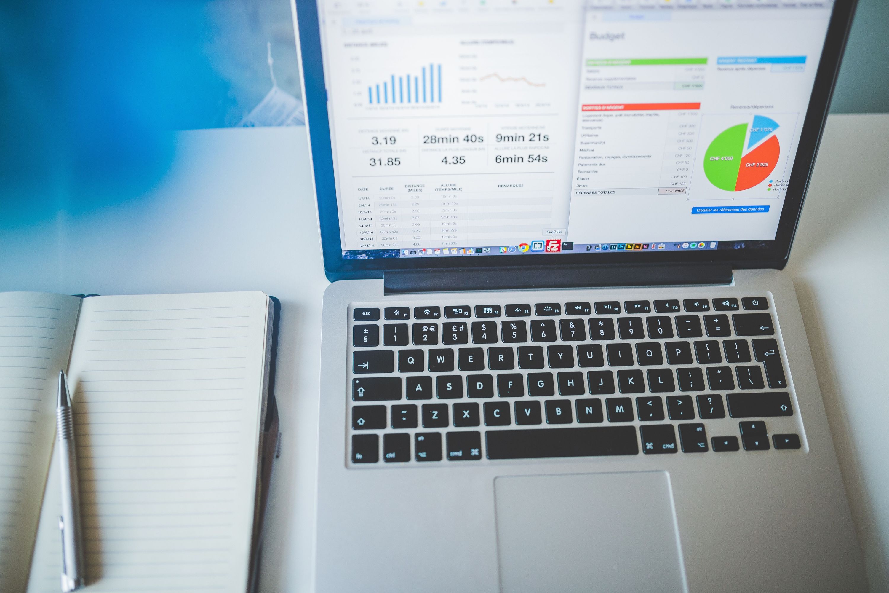 Laptop displaying analytics dashboards beside an open notebook