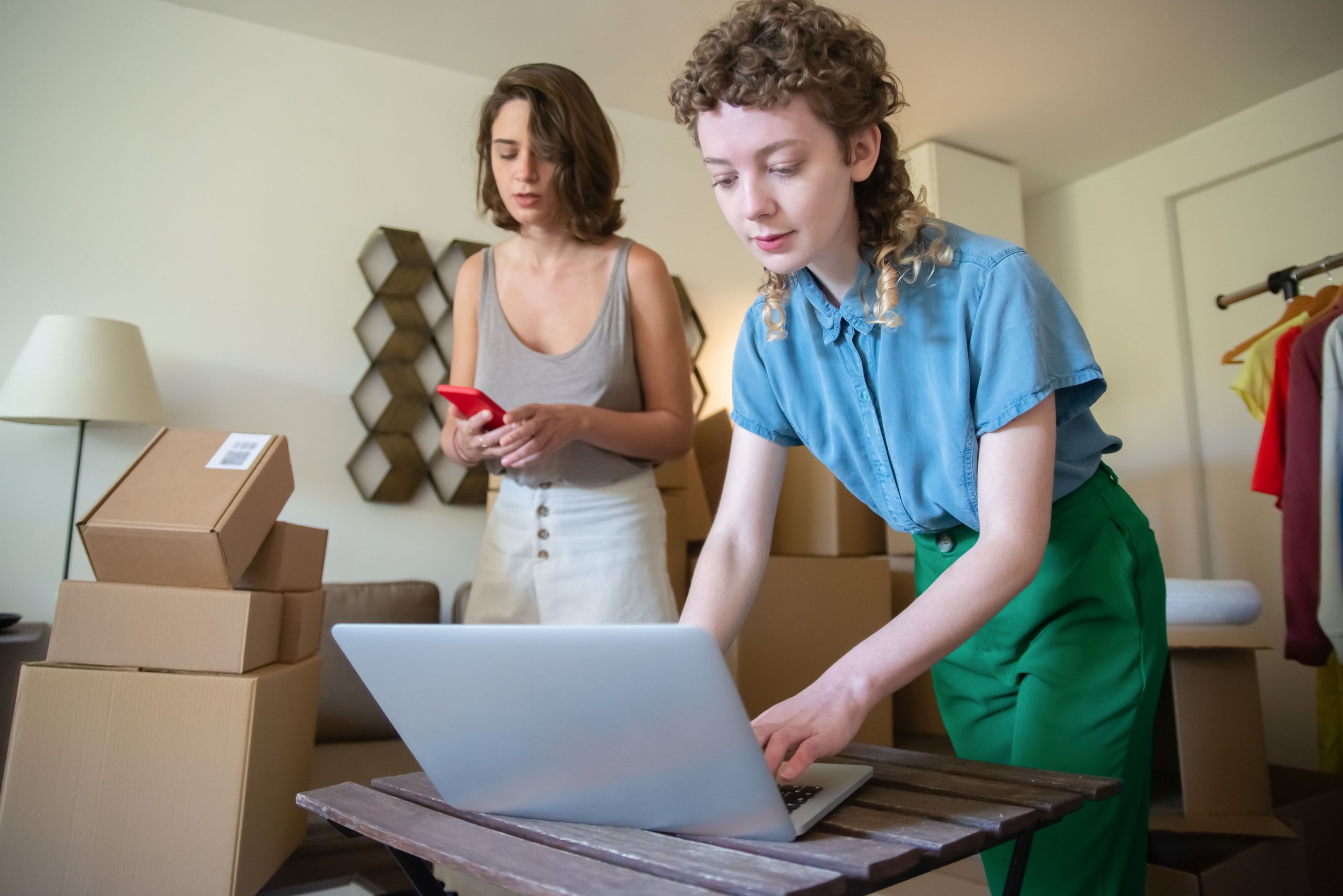 Two ecommerce business owners packing orders while using a laptop