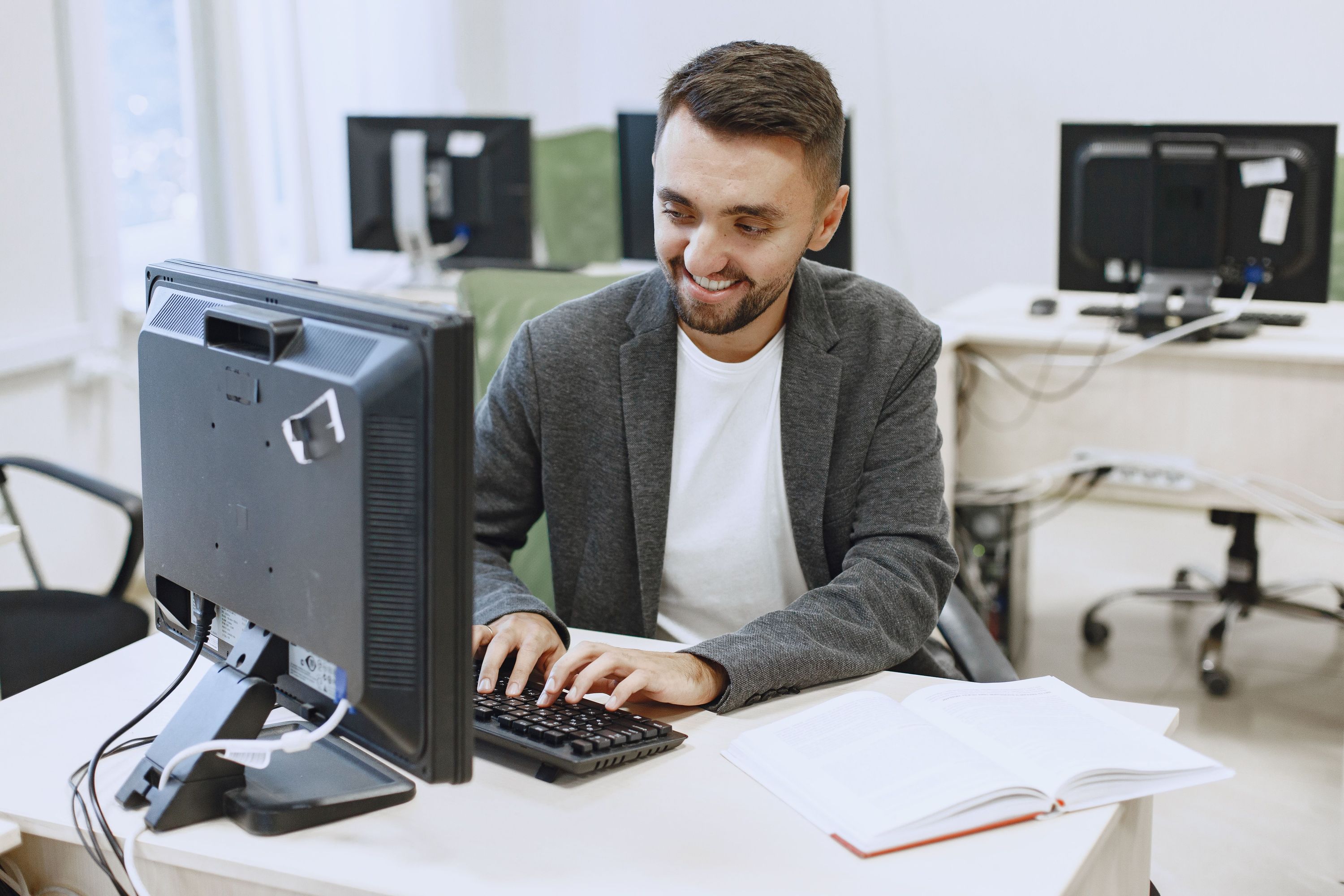 Smiling professional working at a desktop computer in a bright office