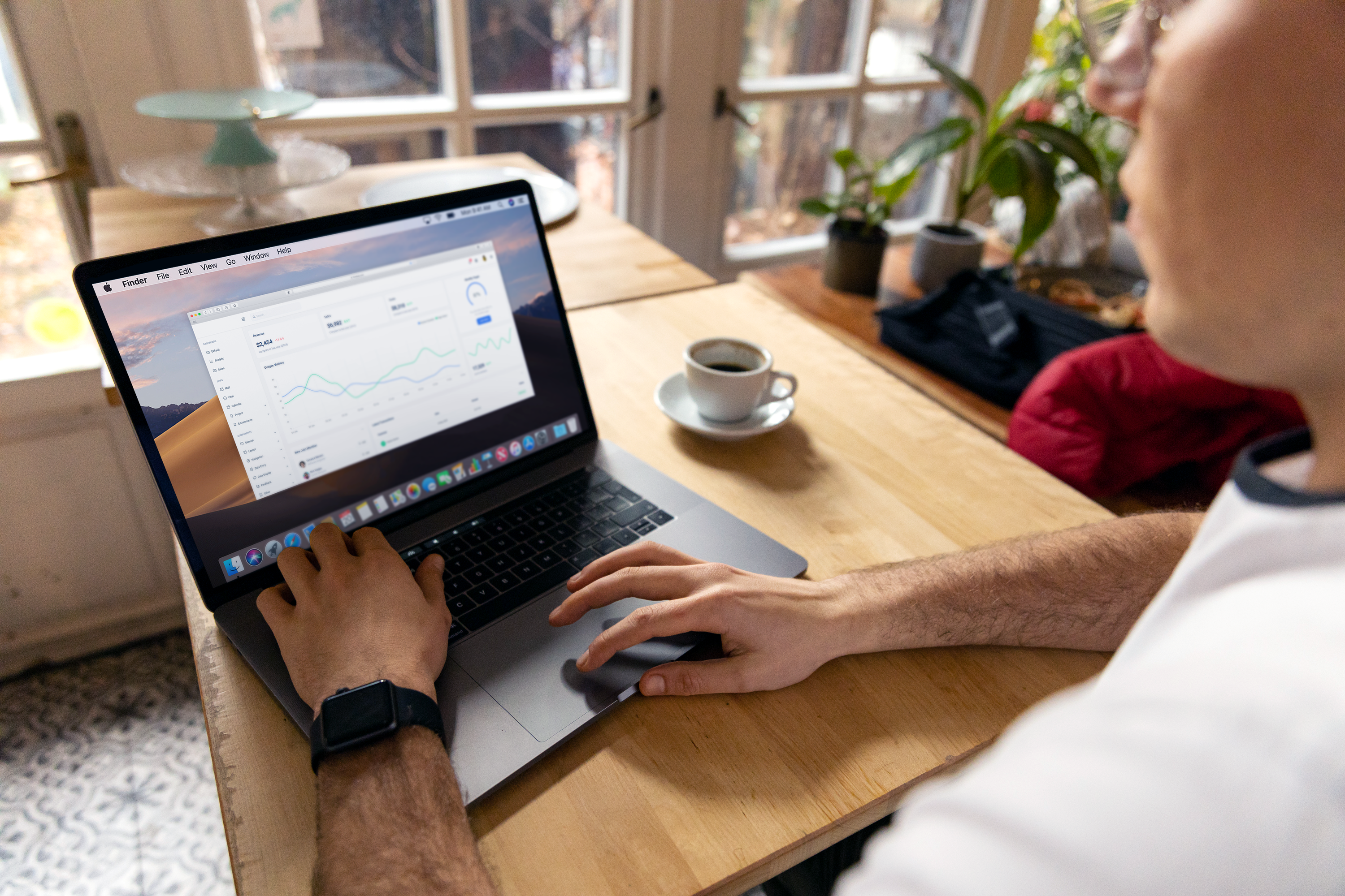 Person reviewing analytics charts on a laptop at a sunlit wooden table