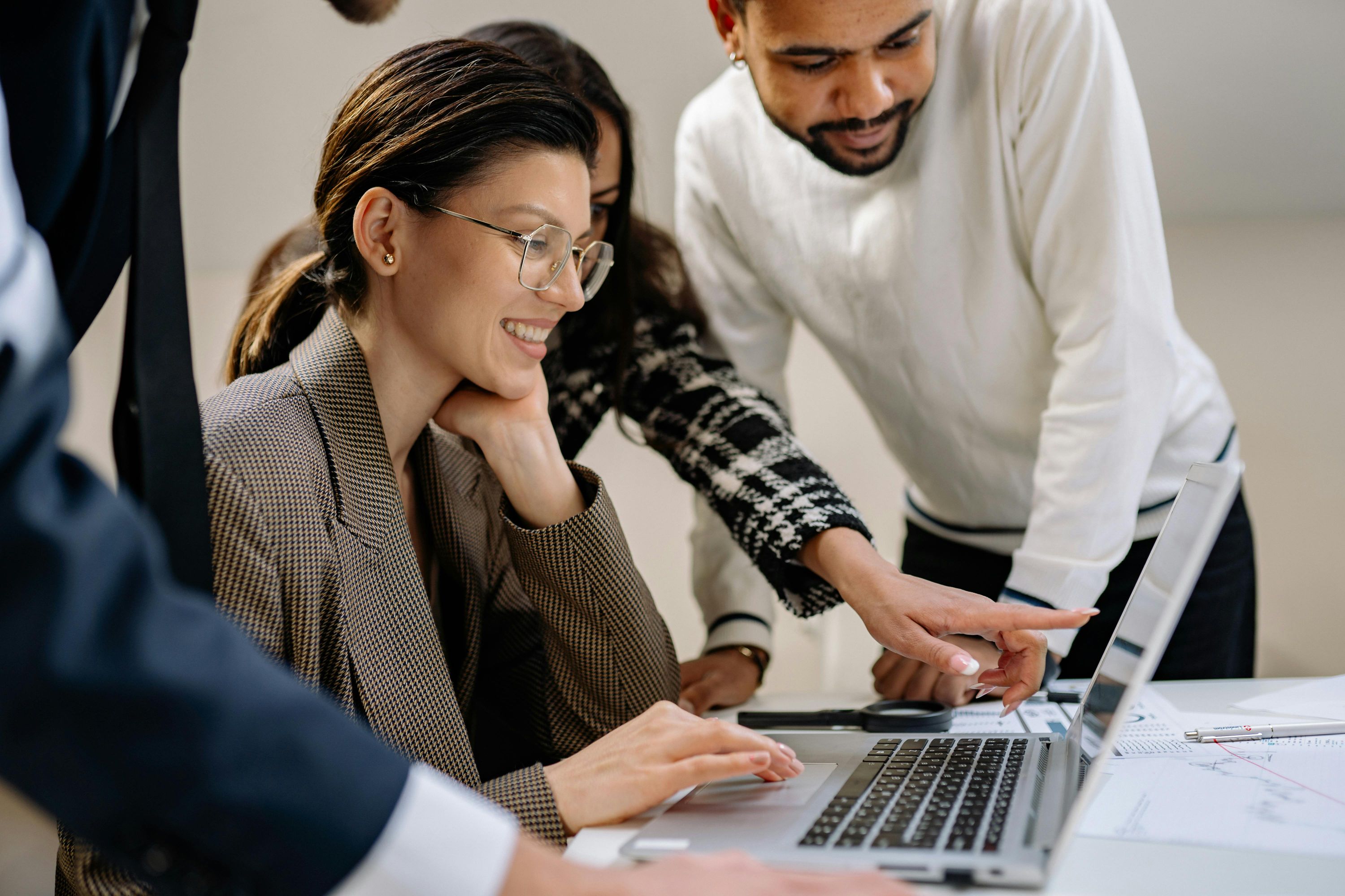 Woman in eyeglasses smiling while using a laptop to build marketing landing pages