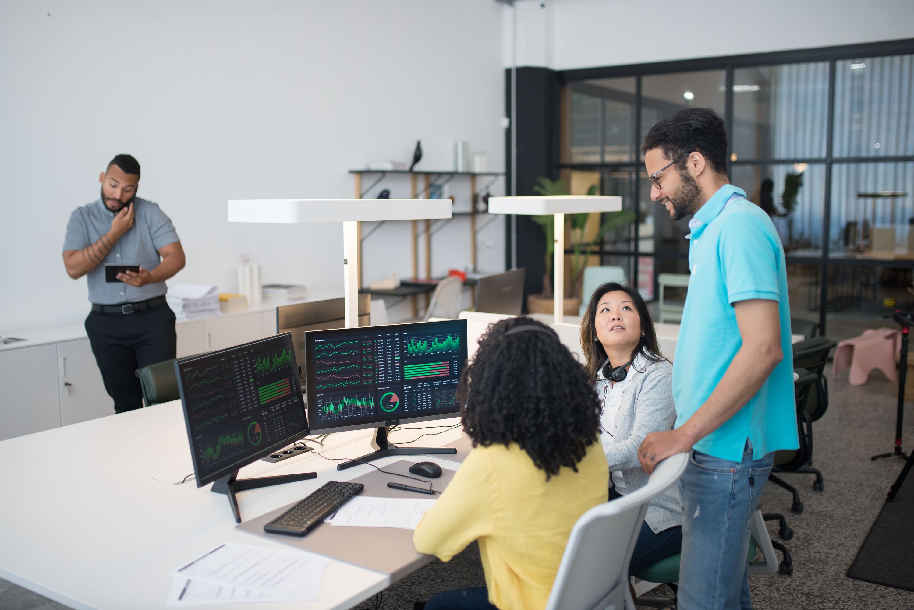 Colleagues reviewing charts and analytics on computer monitors in a modern office