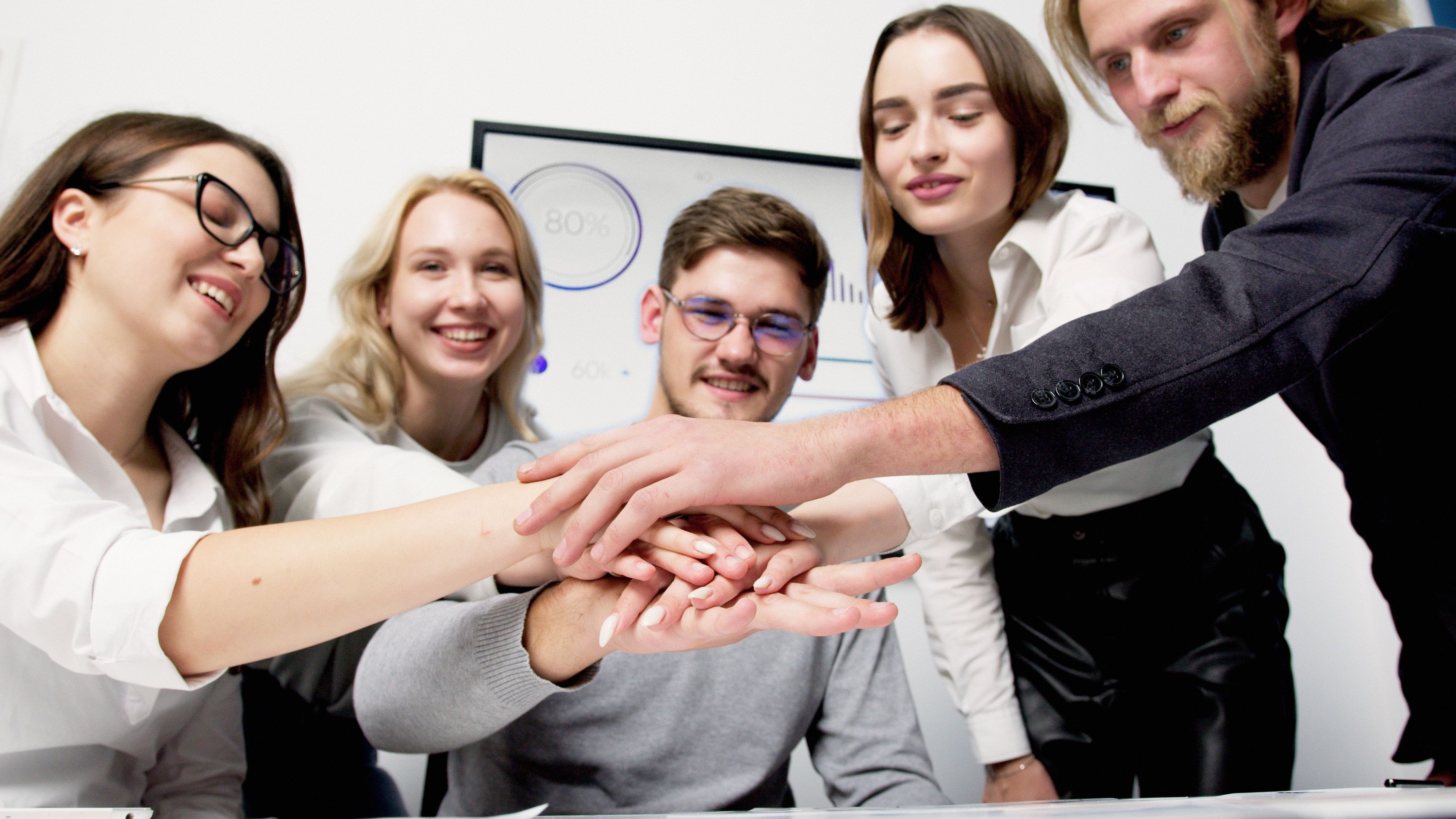 A group of professionals joining hands in teamwork in a modern office setting
